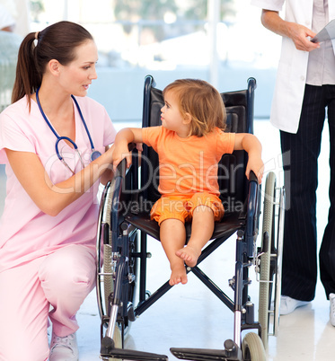 Young nurse talking to a baby in a wheelchair