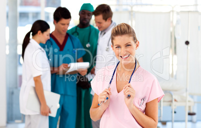 Portrait of a smiling nurse with her team in the background