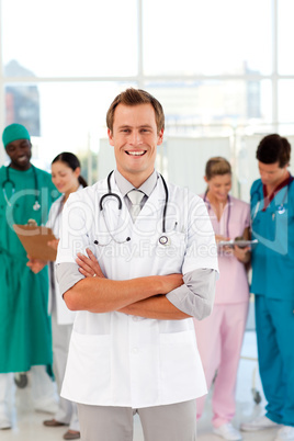 Young and smiling doctor with his team in the background