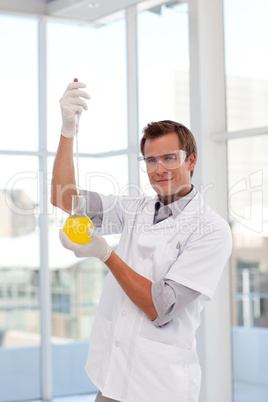 Scientist examining a test-tube looking at the camera