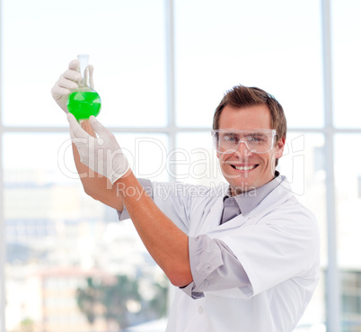 Scientist examining a test-tube smiling at the camera