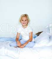 Smiling blonde girl sitting on a bed