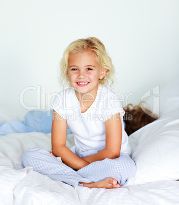 Little girl sitting on bed smiling at the camera