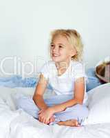 Little girl in bed smiling while her brother is sleeping