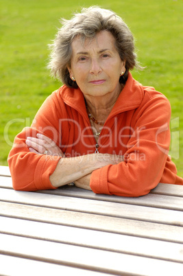 Seniorin sitzt an einem Holztisch