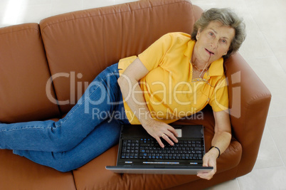 Seniorin mit Laptop auf Couch