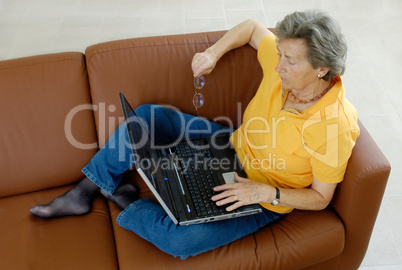 Seniorin mit Laptop auf Couch