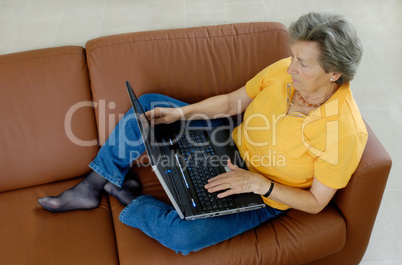 Seniorin mit Laptop auf Couch