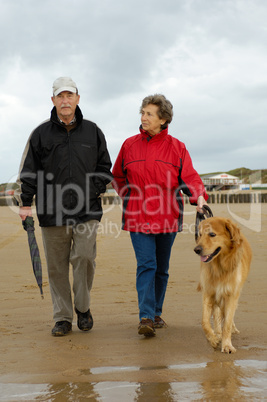 Seniorenpaar mit Hund beim Strandspaziergang