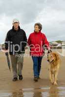 Seniorenpaar mit Hund beim Strandspaziergang