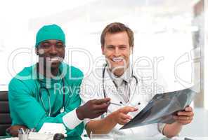 doctor and surgeon looking at an xray and smiling at camera