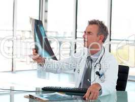 Senior Mature Doctor working at his desk in a hospital