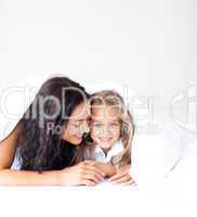 Mother and daughter on bed smiling at camera