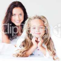 Mother and daughter on bed smiling at camera