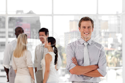 Attracive and confident business man in front of a group of associates smiling