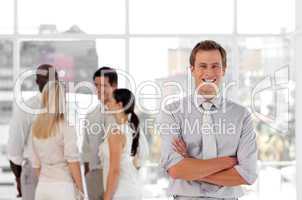 Attracive and confident business man in front of a group of associates smiling