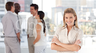 Business woman in front of a group of associates smiling