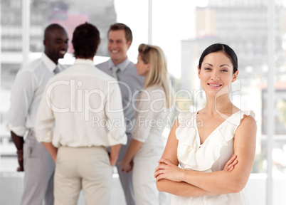 Attracive and confident business woman in front of a group of associates smiling