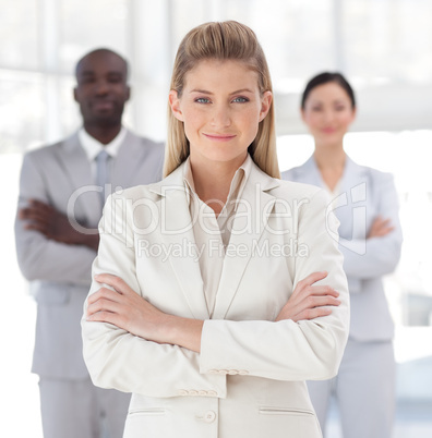 Business woman with folded arms in front of associates