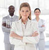 Business woman with folded arms in front of associates