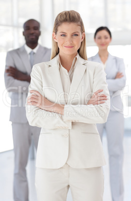 Business woman with folded arms in front of associates