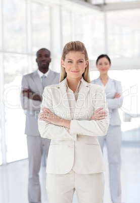 Business woman with folded arms in front of associates