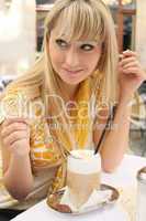 young blond woman in a cafe with latte macchiato