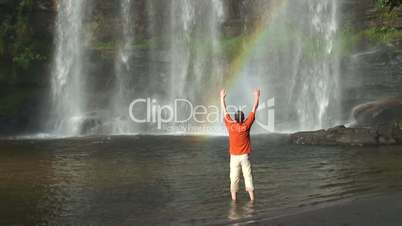 Mann vor Wasserfall mit Regenbogen