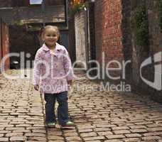 Young black baby girl playing on cobble stoned alley