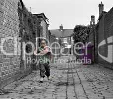 Young black baby girl playing on cobble stoned alley