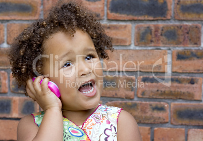 Young black baby girl talking on a toy cell phone