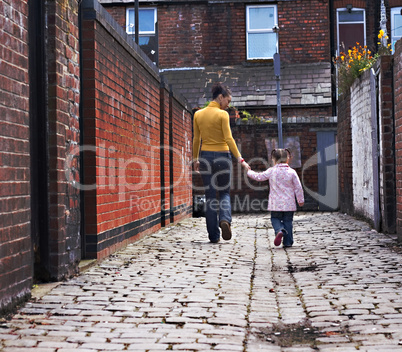 Young mother and daughter walking down cobblestone alley