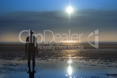 Iron statue on the beach silhouette against a clear blue sky