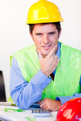 Junger Mann mit Schutzhelm am Schreibtisch.