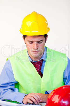 Junger Mann mit Schutzhelm am Schreibtisch.