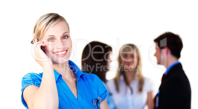 Businesswoman on phone with her team in the background