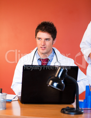 Attractive doctor using a laptop in office