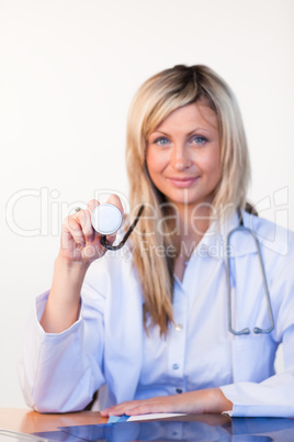 Smiling blonde doctor showing a stethoscope to the camera