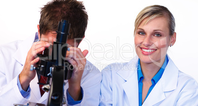 Woman smiling at the camera and male scientist looking through a
