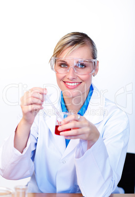 Female scientist examining a test-tube and smiling at the camera