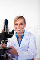 Blonde scientist with a microscope smiling at the camera