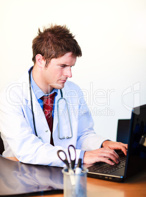 Thoughtful  young doctor working on a computer