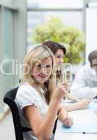 Smiling businesswoman drinking champagne in office