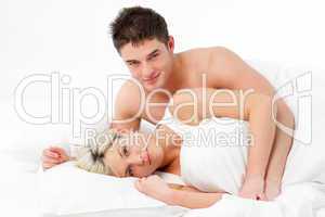 Young couple lying on bed and smiling at the camera