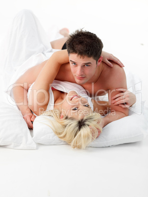 Couple lying on bed smiling at the camera