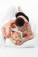 Happy young couple lying on bed