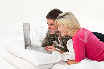 Boy using a latop in bed with his girlfriend