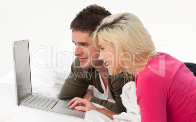 Portrait of a couple using a latop in bed