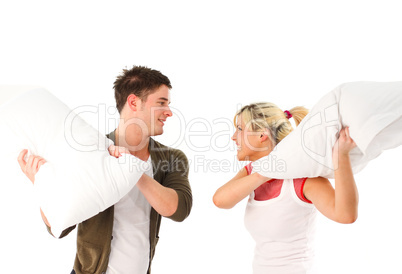 Young girl and boy having a pillow fight