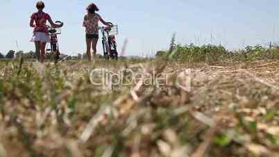 Mädchen schieben ihre Fahrräder über Feldweg